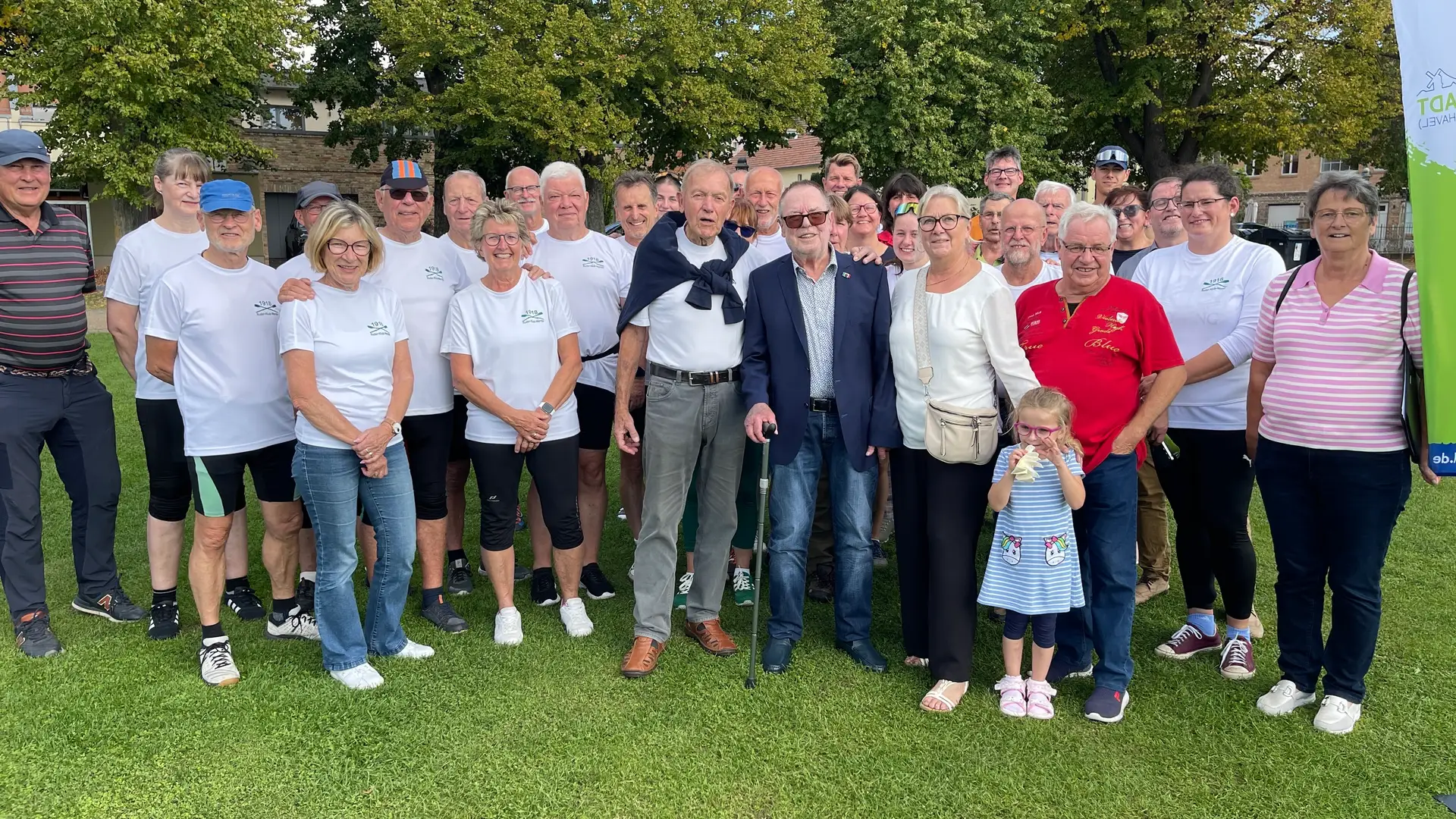 Gruppenfoto mehrerer Personen, darunter Werner Große und Manuela Saß, vor einem städtischen Hintergrund.