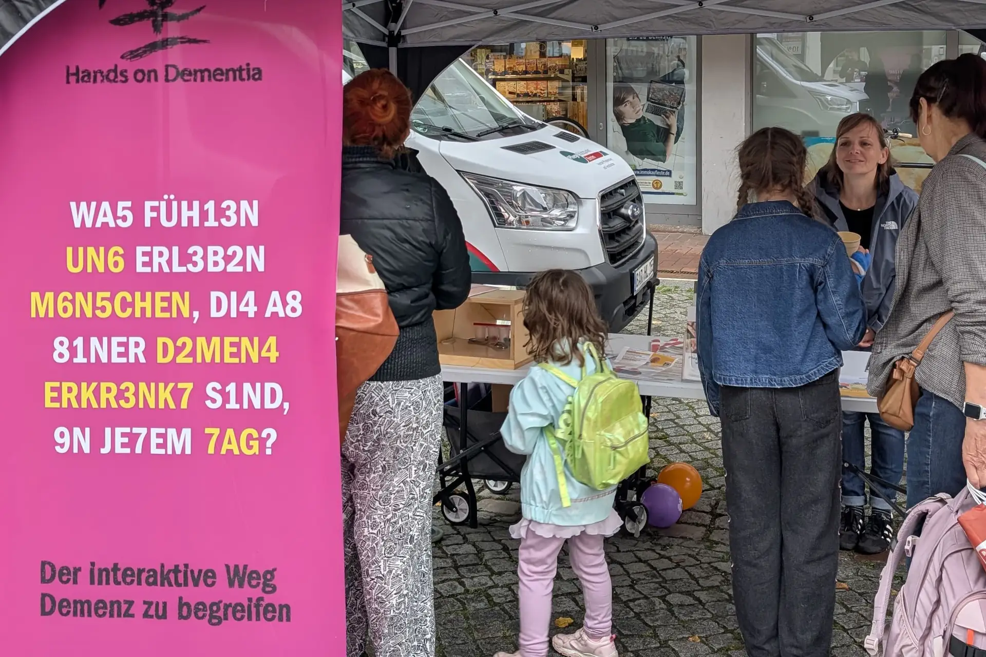 Infostand zum Thema Demenz mit Schautafeln und Informationsmaterialien, Personen stehen im Umfeld des Standes.