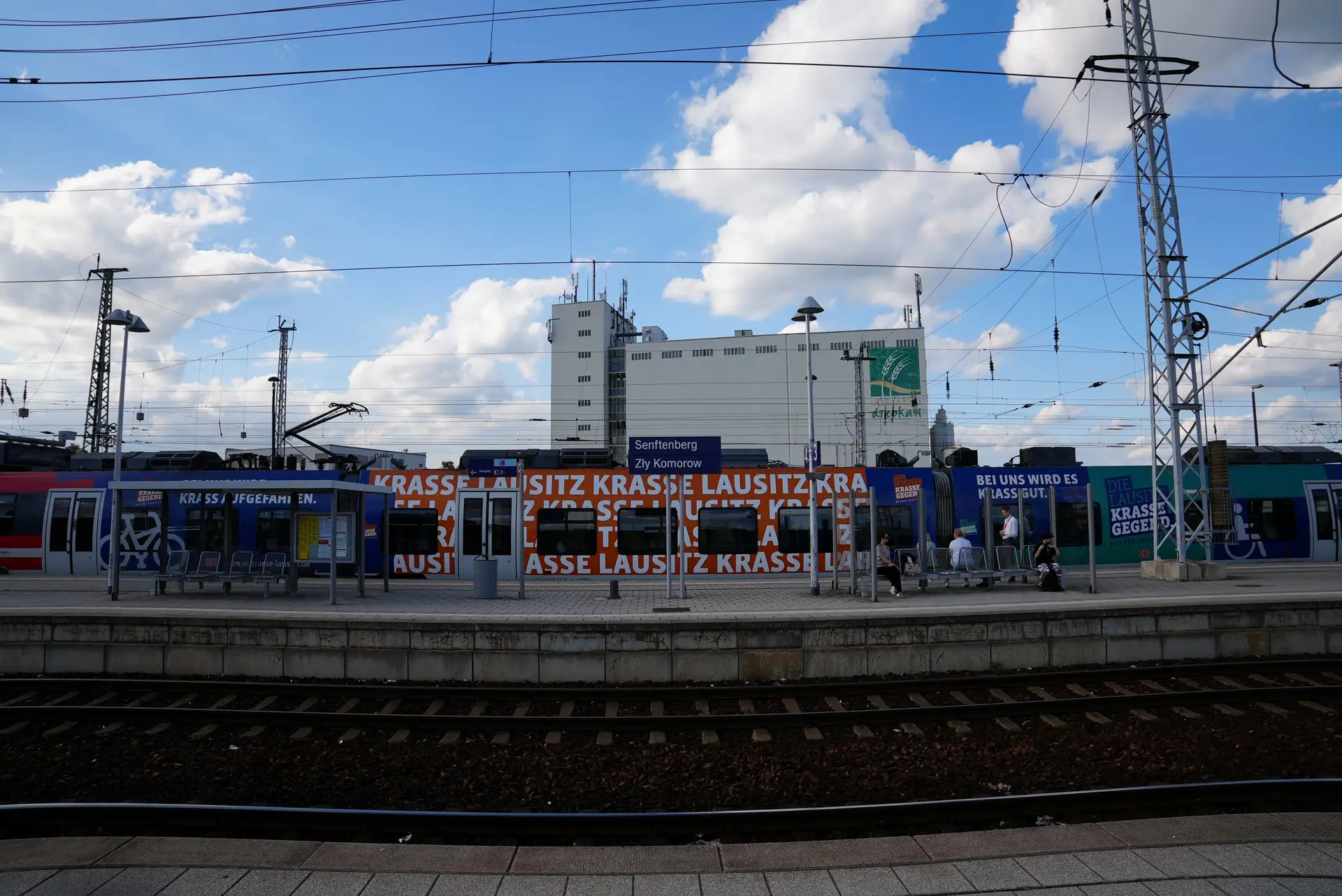 Teilnehmende stehen als Gruppe auf einem Bahnhof; im Hintergrund ist die Bahn- bzw. Bahnhofsszene erkennbar.