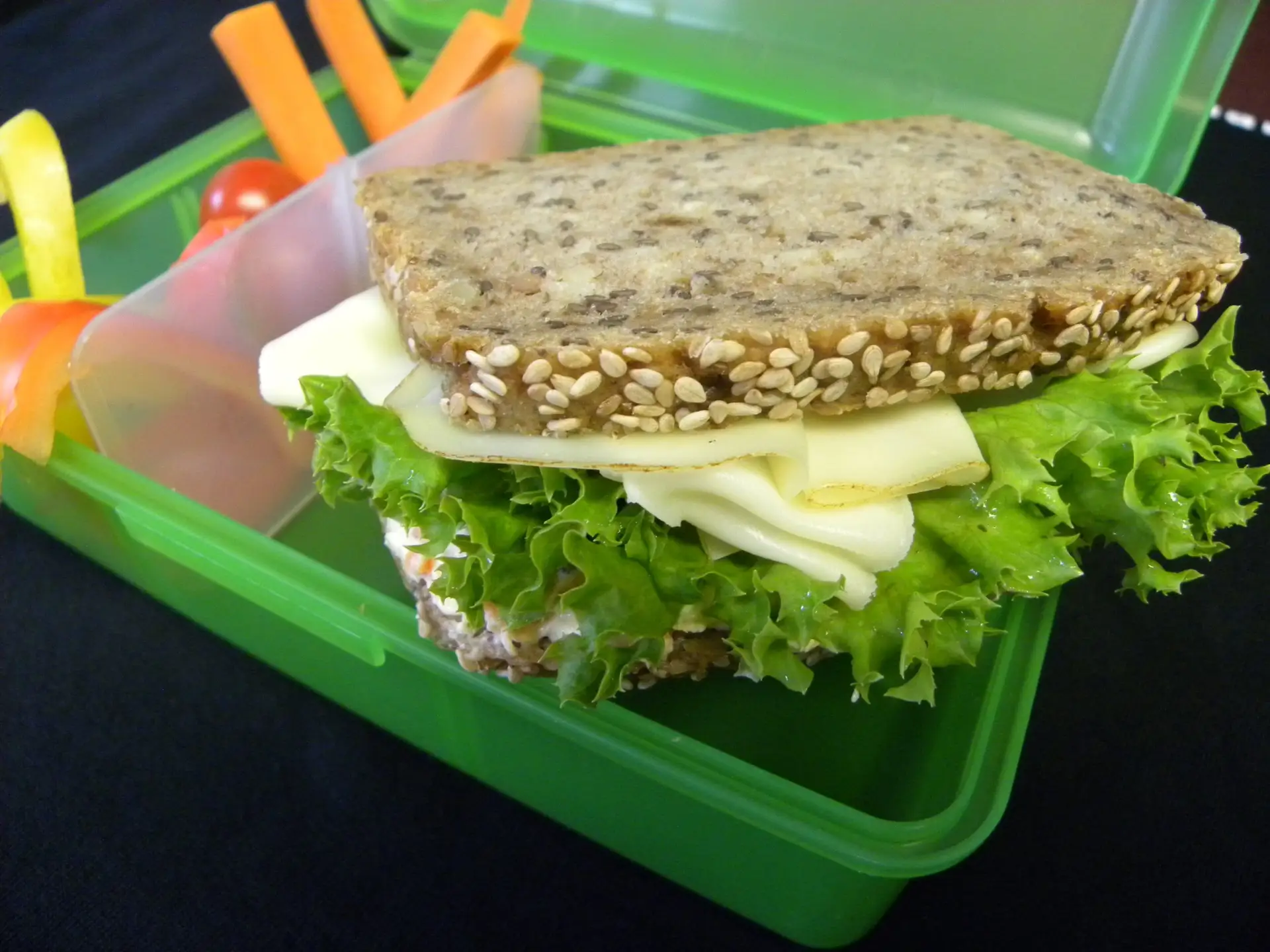 Vollkornbrot mit Käse und Salat sowie knackigem Gemüse als ausgewogenes Pausenfrühstück.