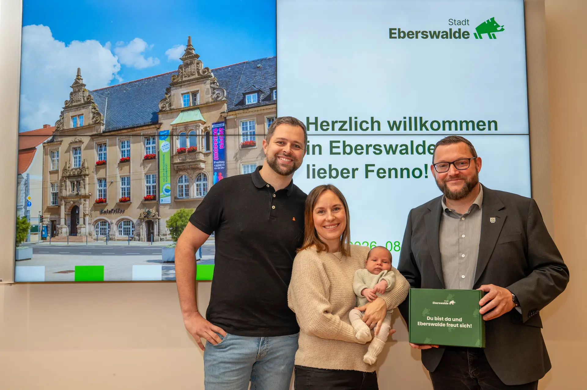 Bürgermeister Götz Herrmann übergibt Fenno und seinen Eltern eine Babygeschenkbox.